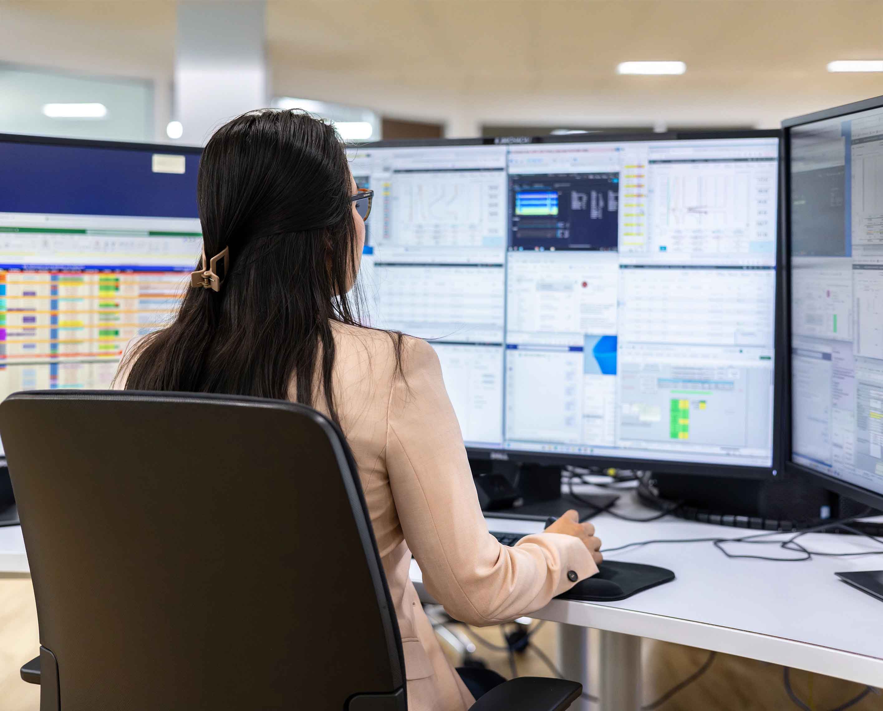 A person at a desk in front of computer monitors