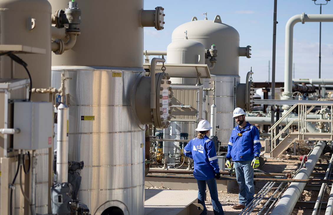 Photo of 2 SLB field personnel near an UltraFab self-contained H2S removal system.