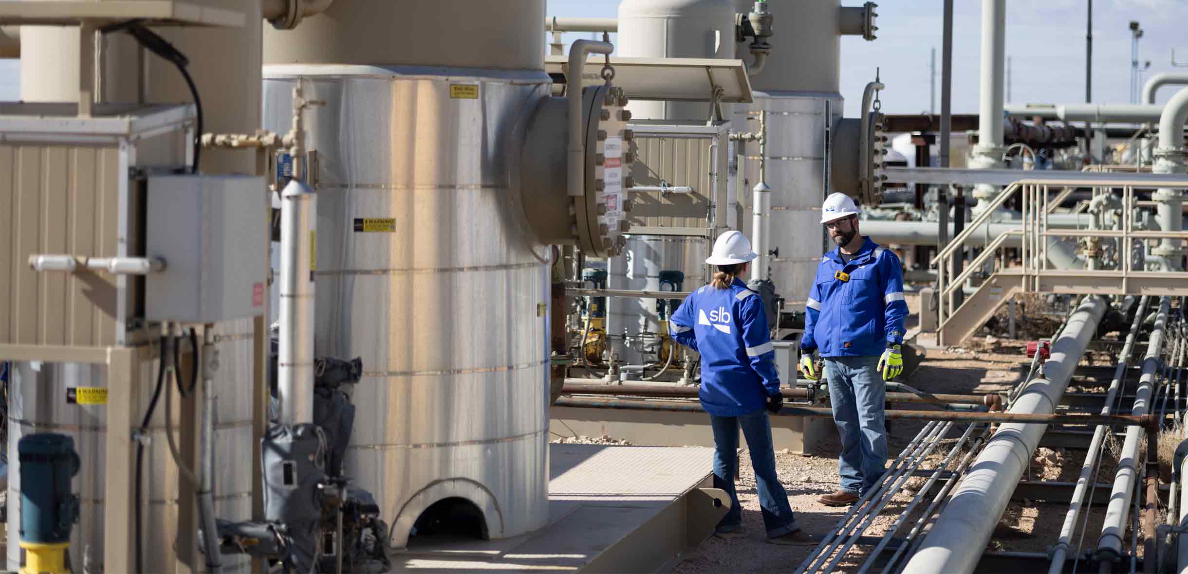 Photo of 2 SLB field personnel near an UltraFab self-contained H2S removal system.