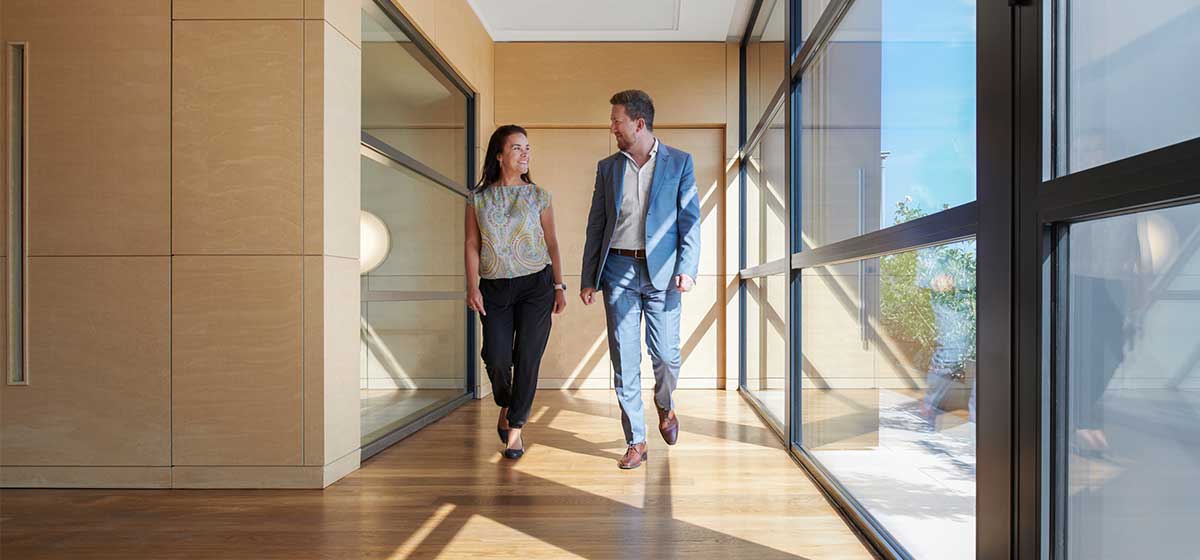 Image shows a woman and a man walking down a corridor.