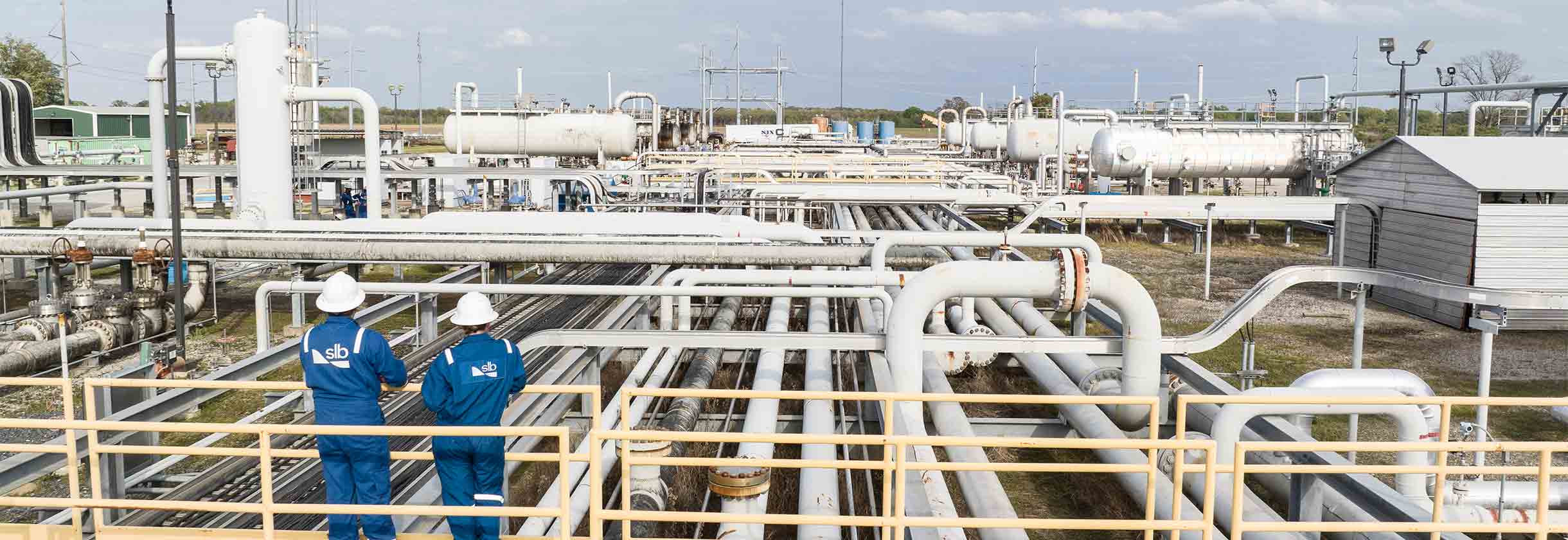 Two SLB operators overlooking a production facility