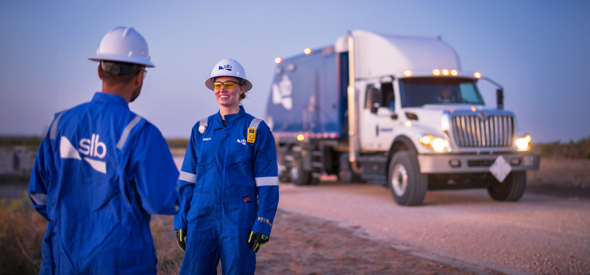 SLB employees next to an SLB wireline truck in the field.