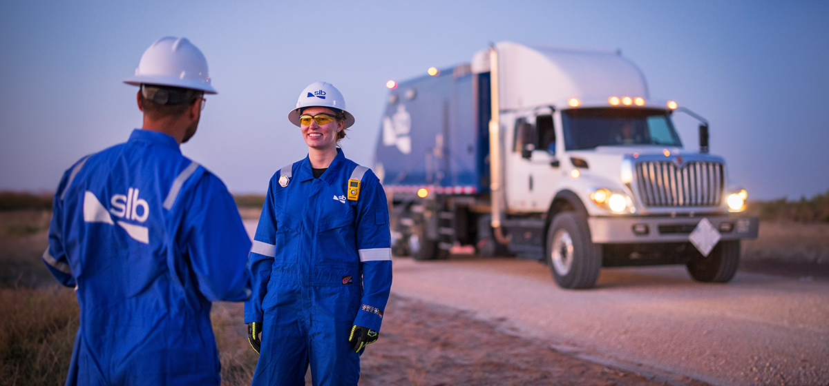 SLB employees next to an SLB wireline truck in the field.