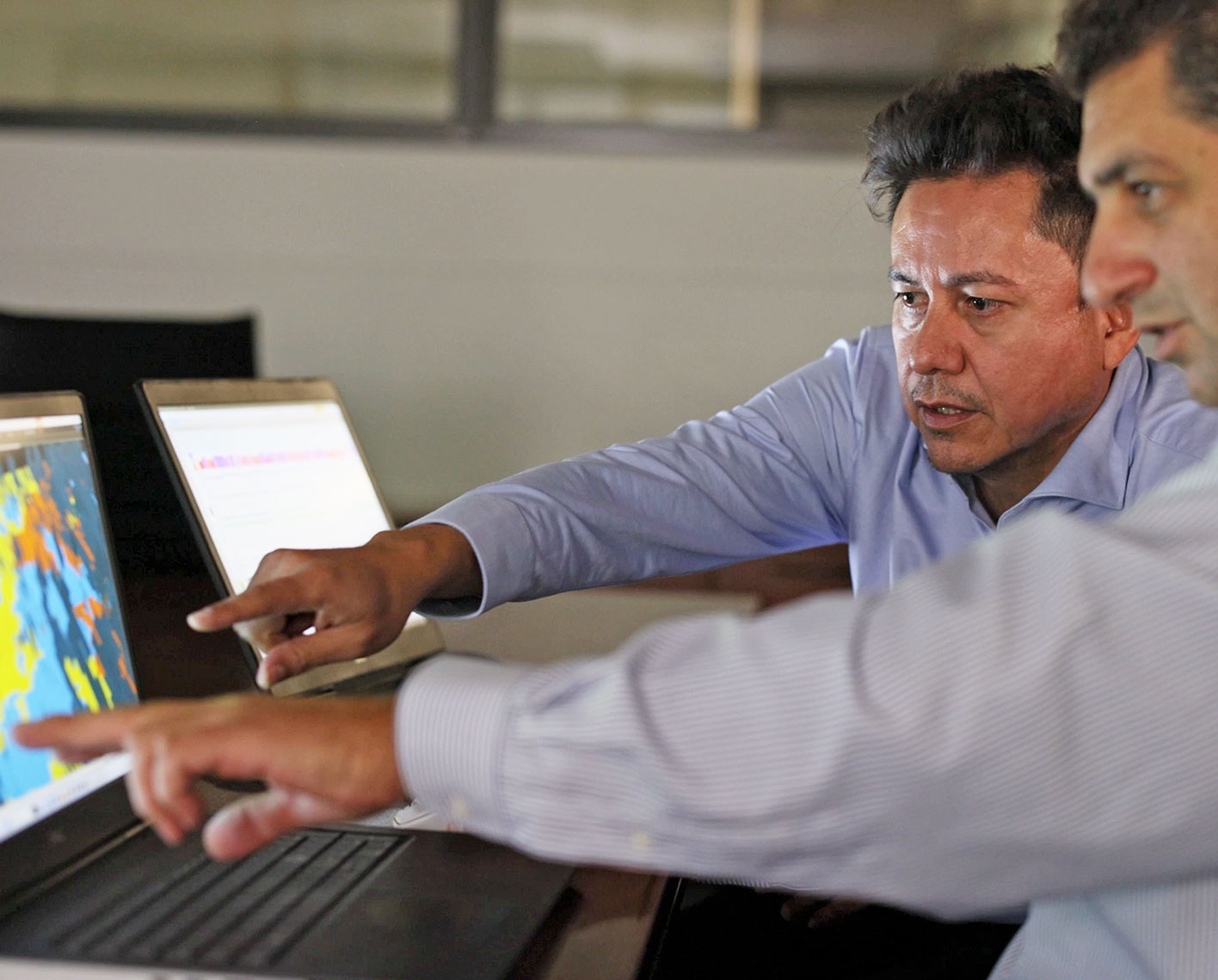 Two engineers looking at data acquired from ThruBit through-the-bit logging services on their screens