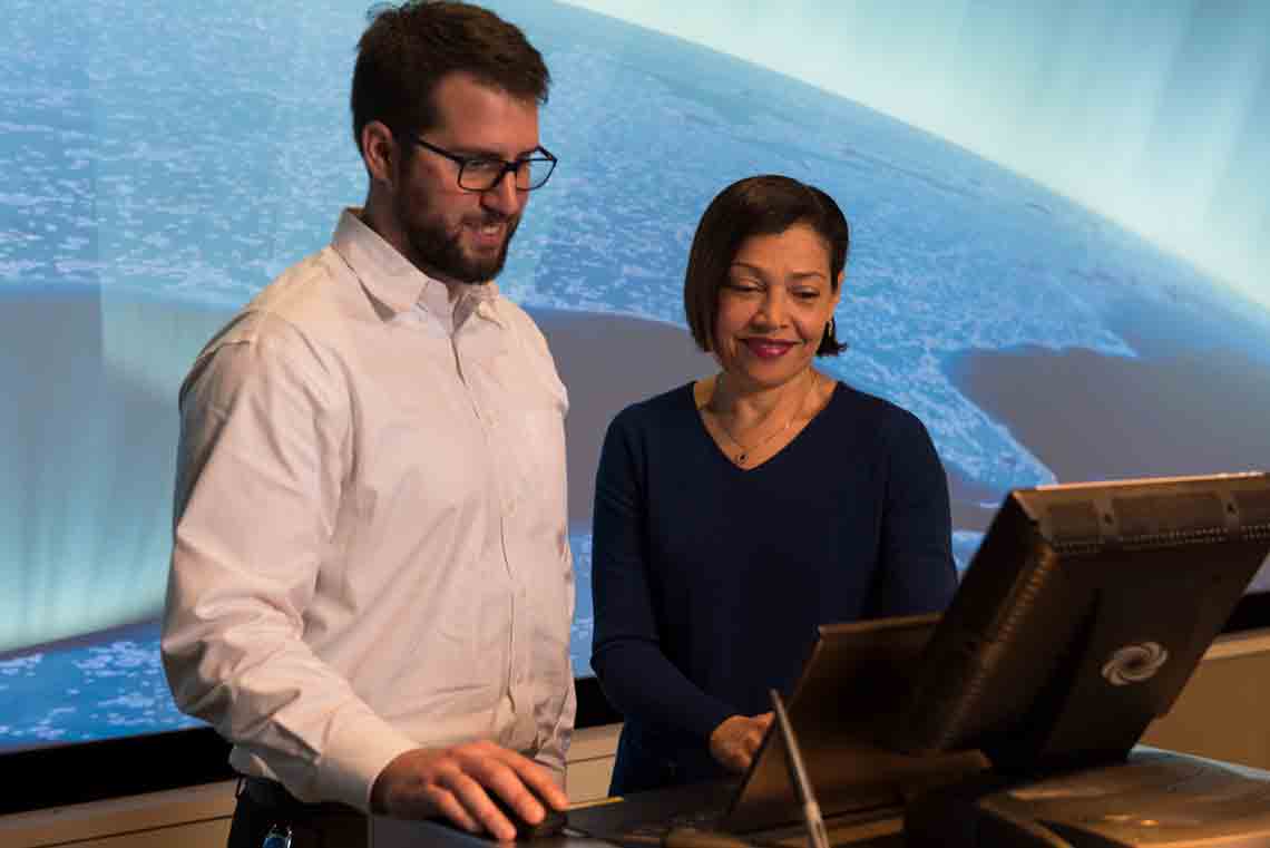 Two presenters looking at seismic processing data