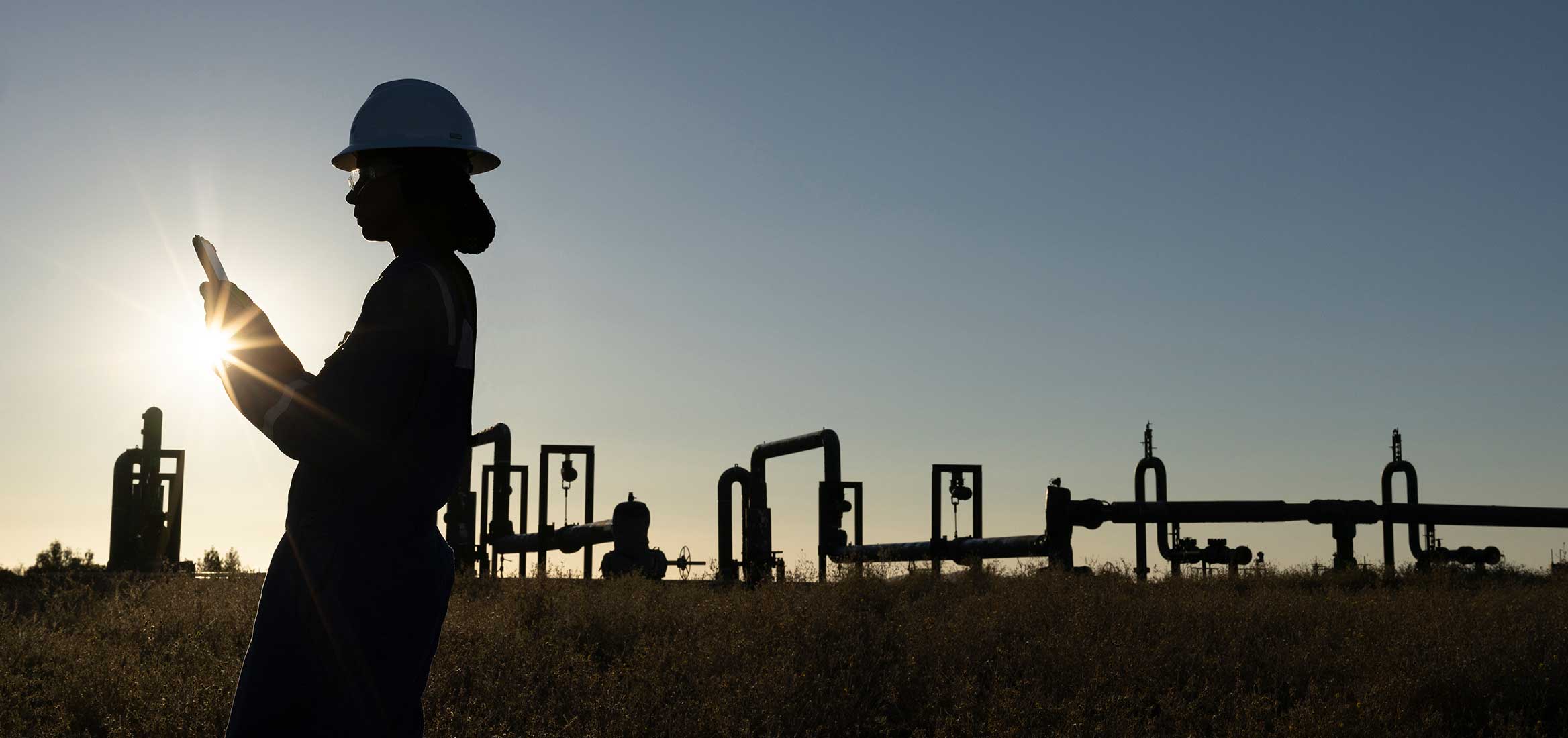 Silhouette of a technician in a geothermal field with piping.