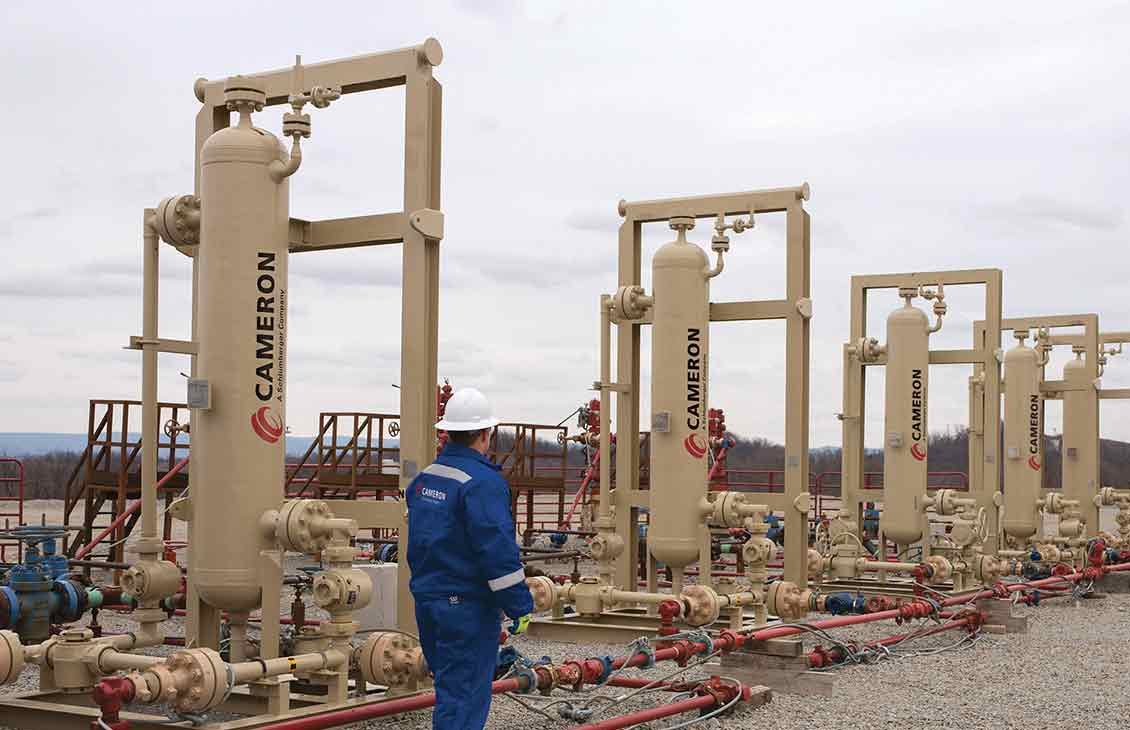 Cameron Worker Standing Next to Sand Separators Equipment in the Field