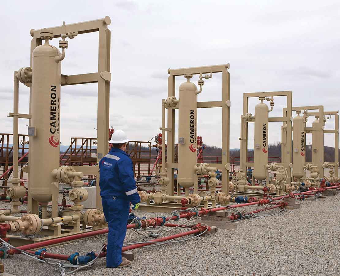 Cameron Worker Standing Next to Sand Separators Equipment in the Field