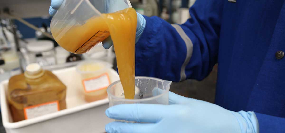Schlumberger lab worker pouring custom-engineered fracturing fluid into a beaker.