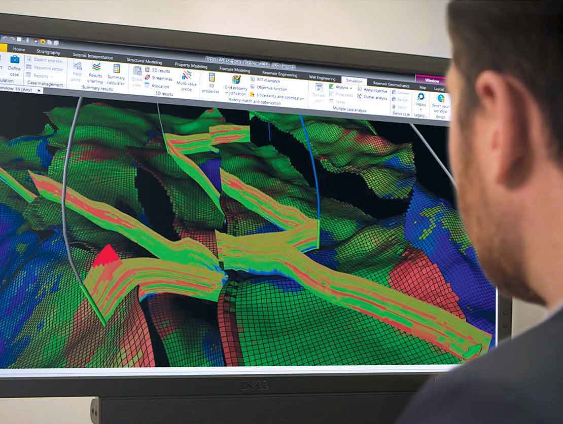 Schlumberger worker looking at monitor with image generated by the Kinetix stimulation software suite.