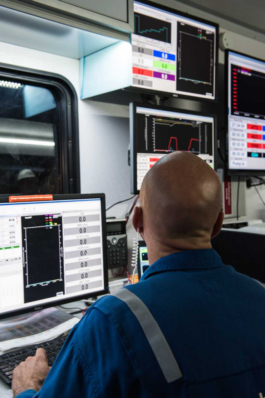 Schlumberger worker looking at monitors displaying data.