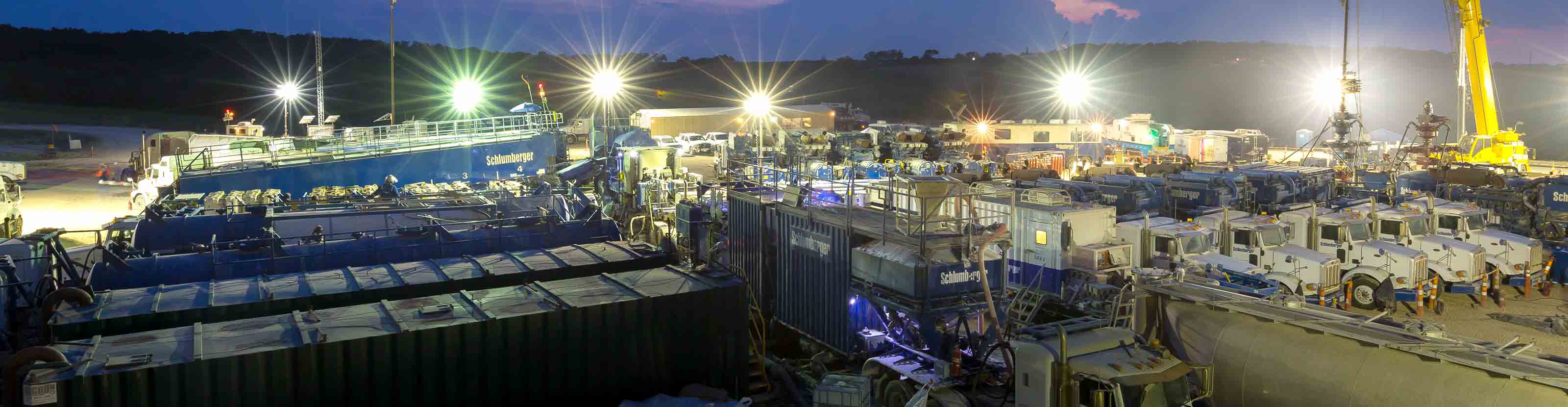 Schlumberger frac fleet on location during night operations on rigsite.