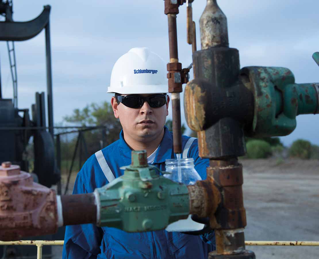 Schlumberger worker in the field looking at equipment.