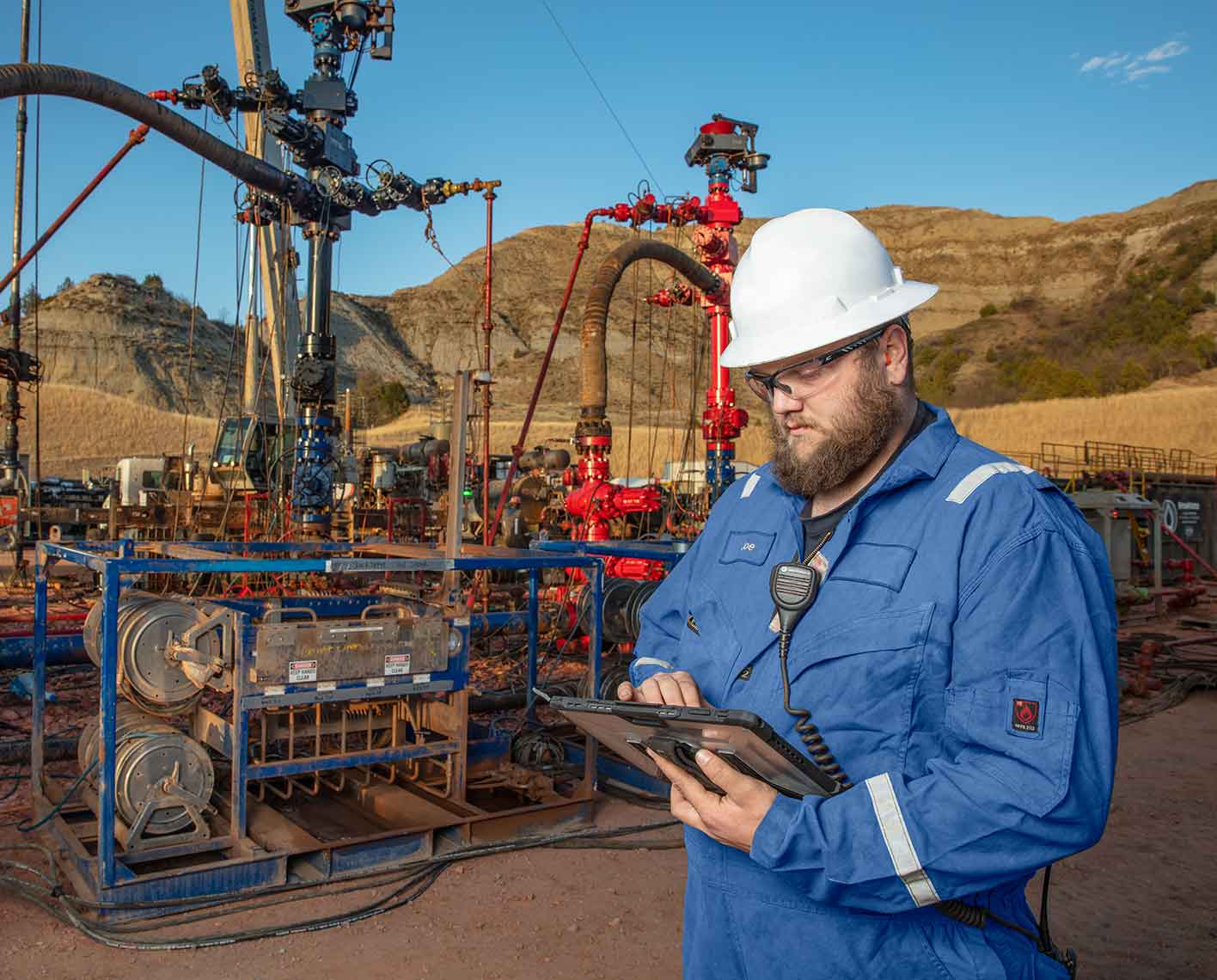 Cameron operator looking at a tablet screen in front of frac trees