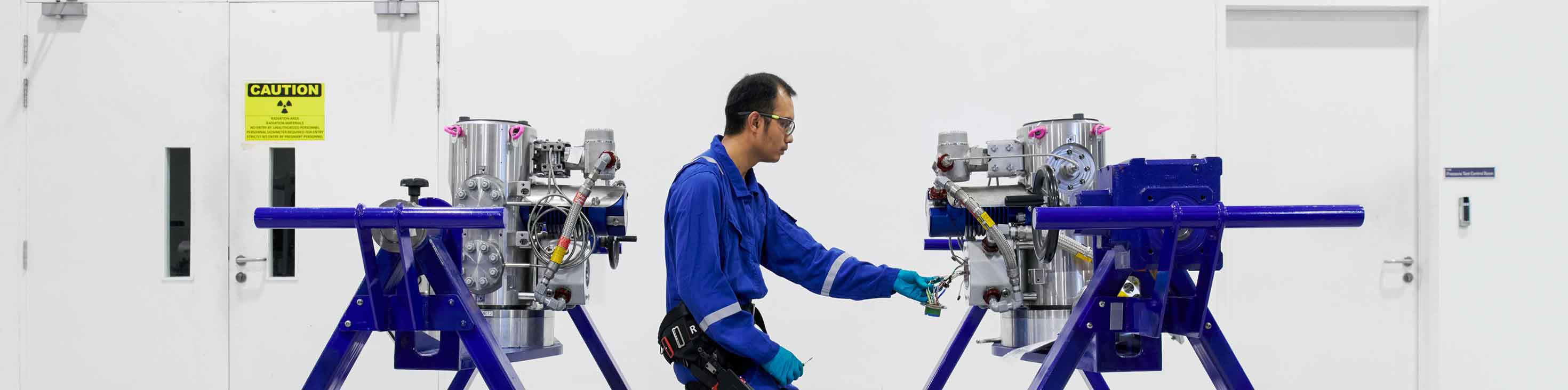 An SLB operator inspecting two Vx Spectra systems in a manufacturing facility