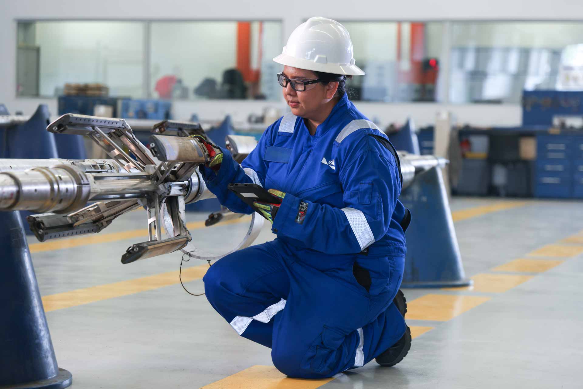 An SLB operator inspecting equipment used in operations, focusing on optimizing reliability, sustainability, and performance 