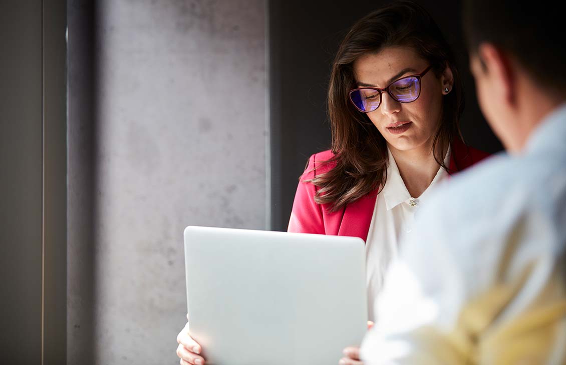 A male and female colleague looking at a laptop.