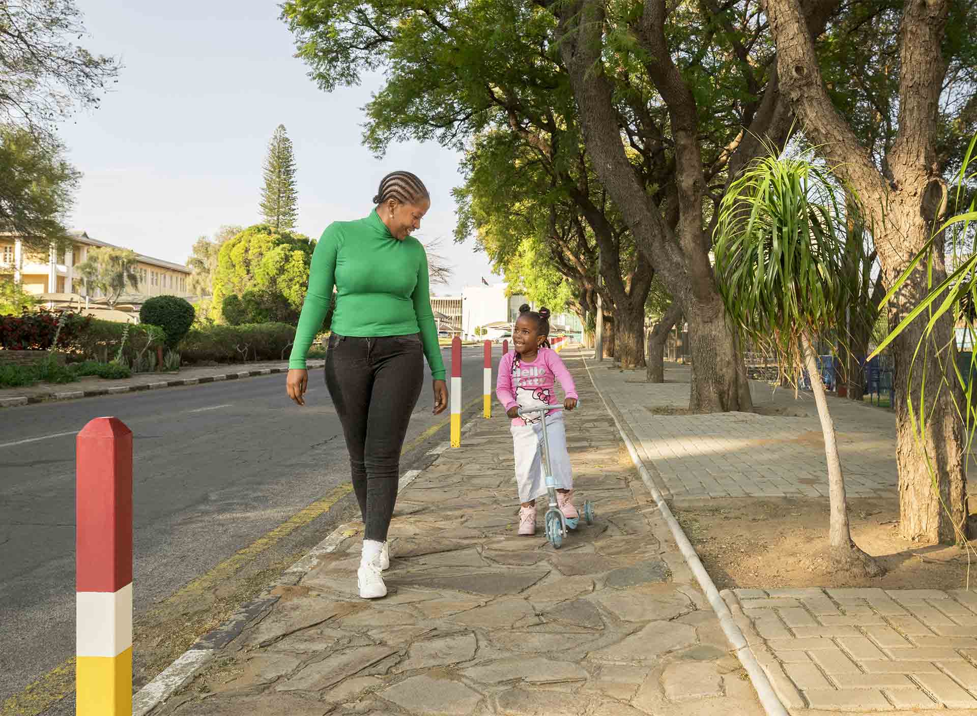 A child walking with her parent on the sidewalk