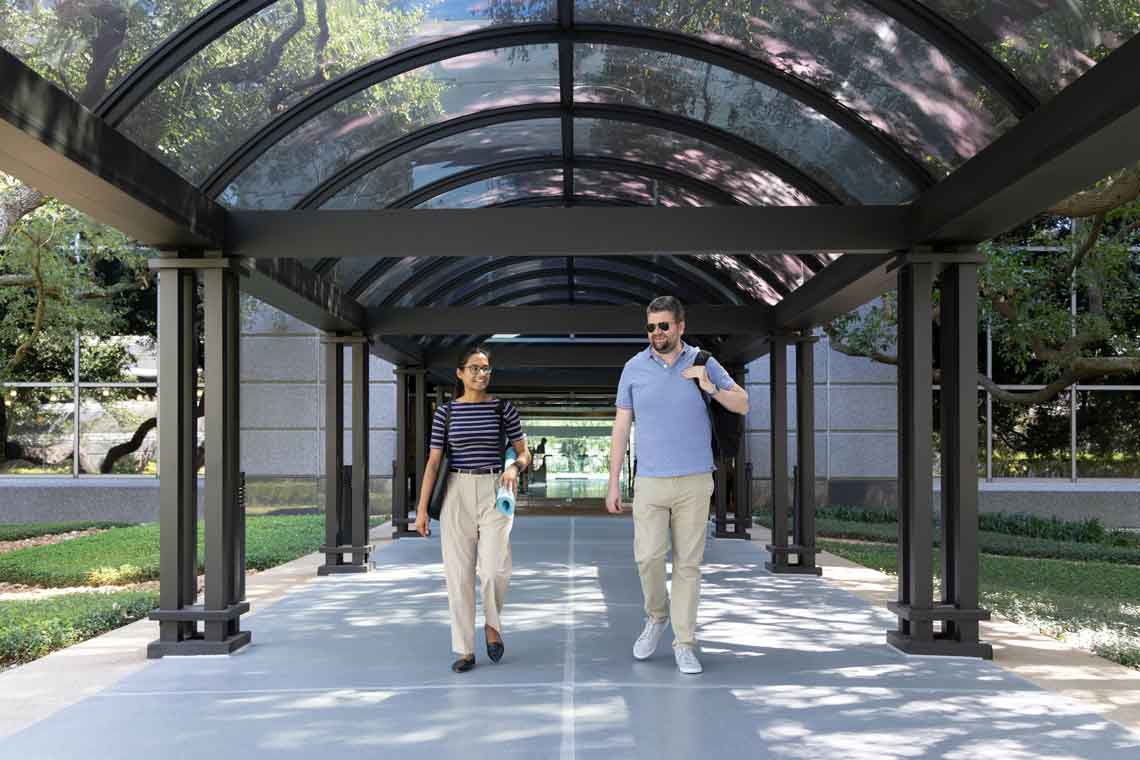 Two people walking together outside under a covered walkway 