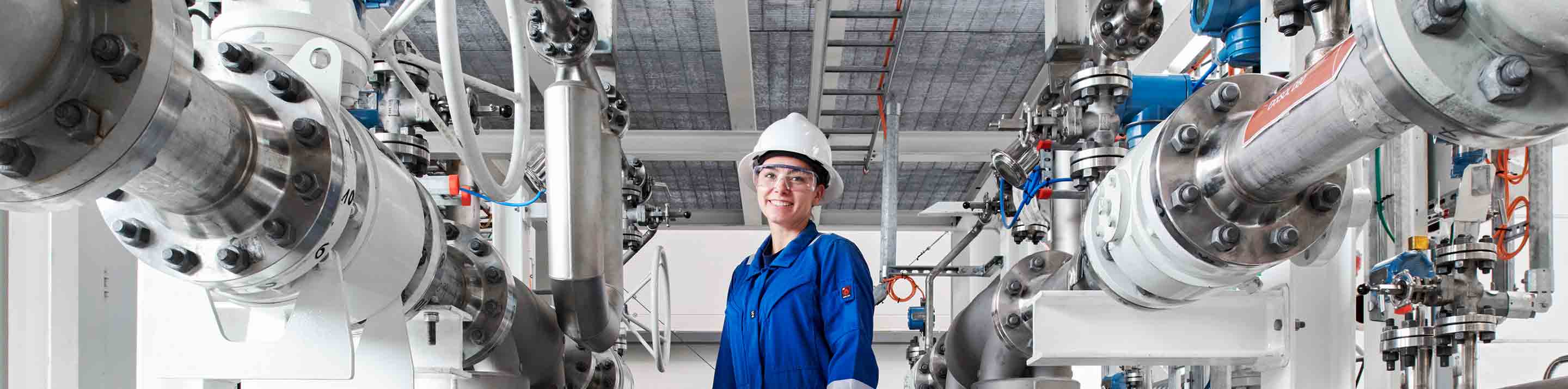 SLB operator standing in a room with pipes, valves, and equipment