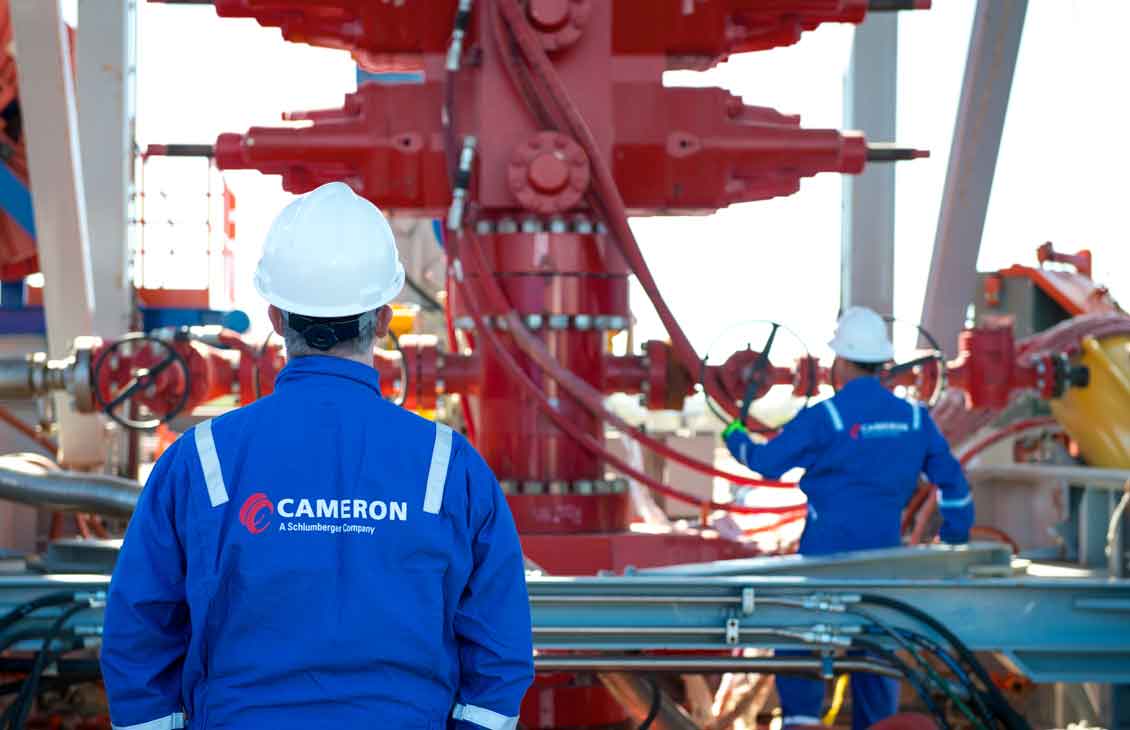 Two Cameron operators inspecting a red BOP