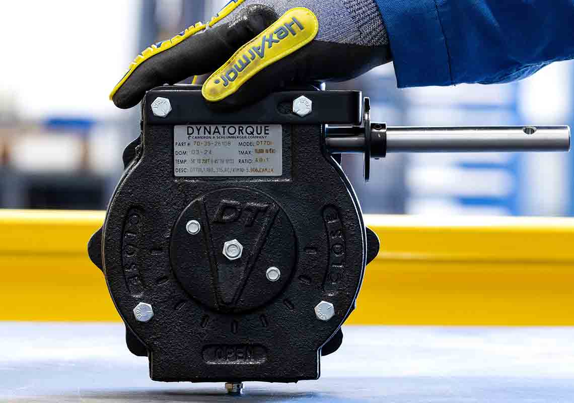 Photo of a gloved hand steadying a Dynatorque severe-service gear in the workshop.