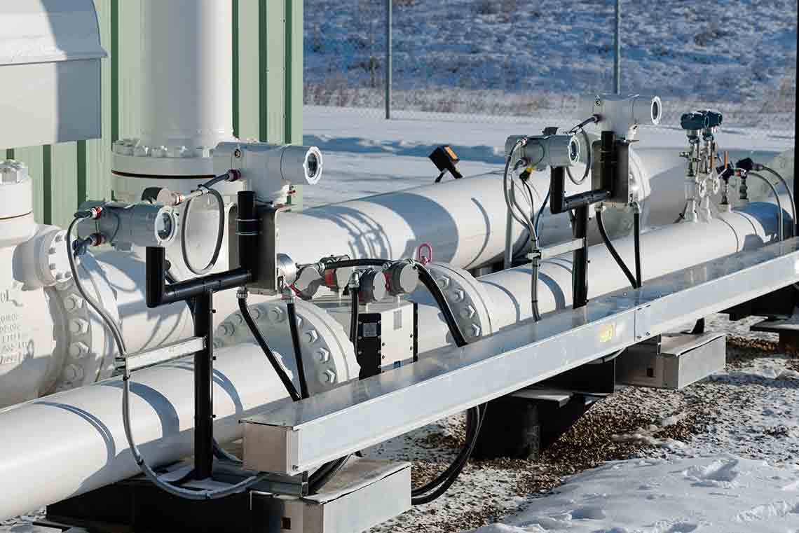 Photo of pipes fitted with measurement devices, in a snowy enclosure.