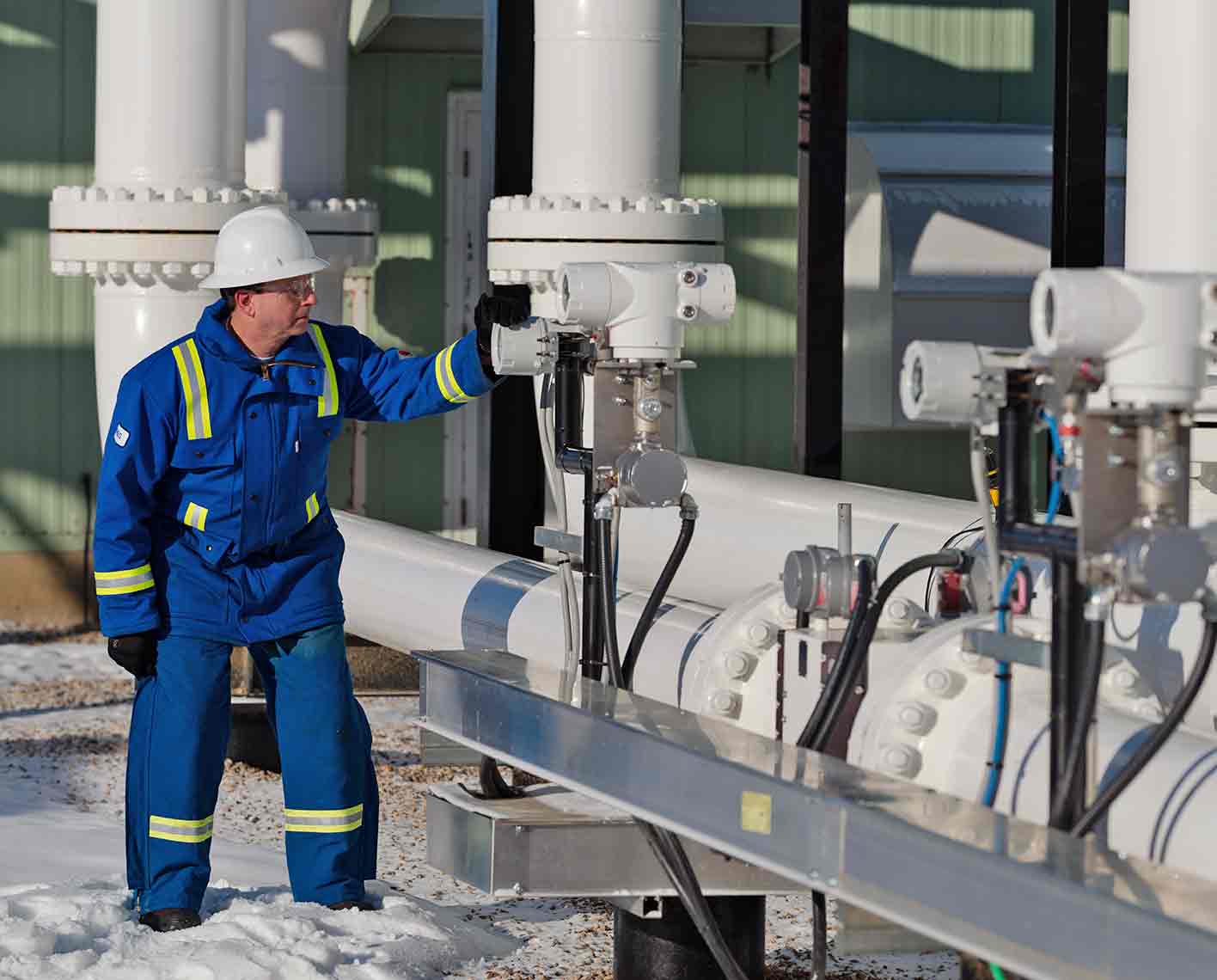 Photo of SLB operative monitoring measurement transducers along pipes at a processing plant.