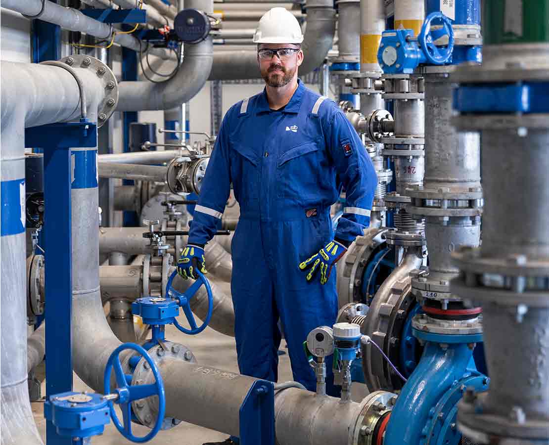 Photo of SLB operator in a plant with valves and piping.