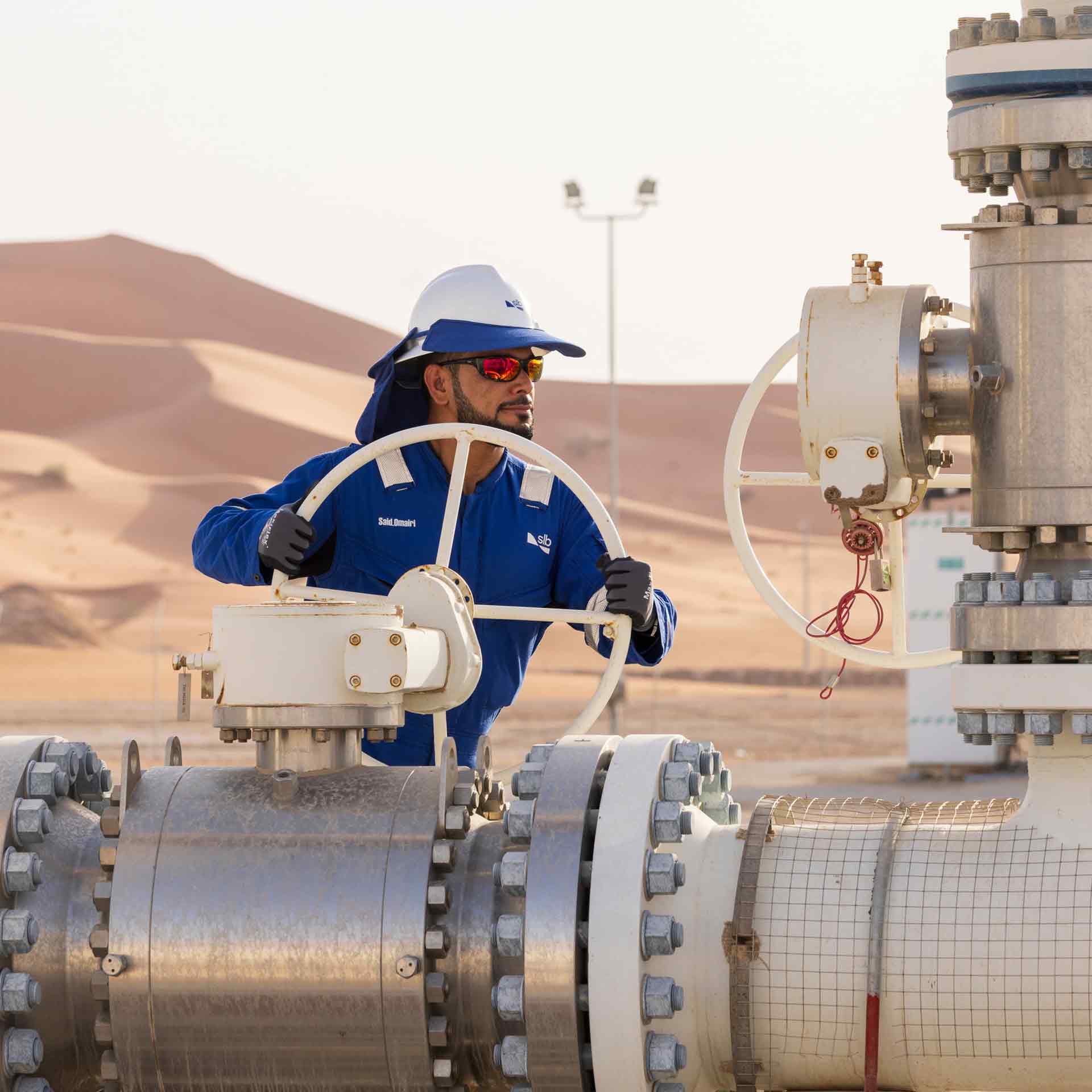 SLB employee standing near large valve equipment at a processing facility.