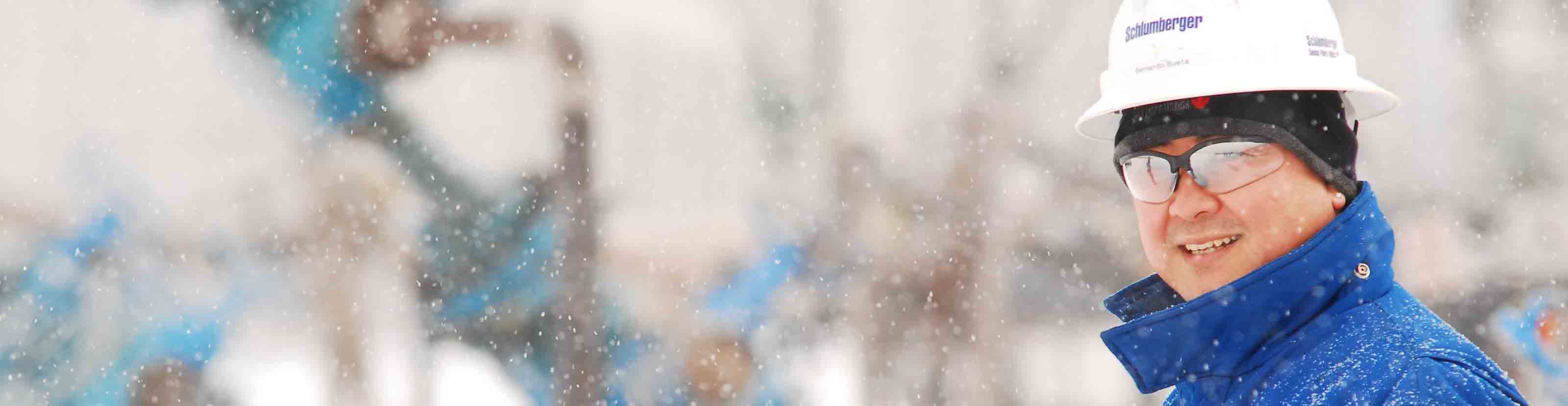 Schlumberger worker standing in the snow smiling while on a rigsite.